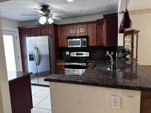 a kitchen with stainless steel appliances granite countertop a stove a sink and a microwave