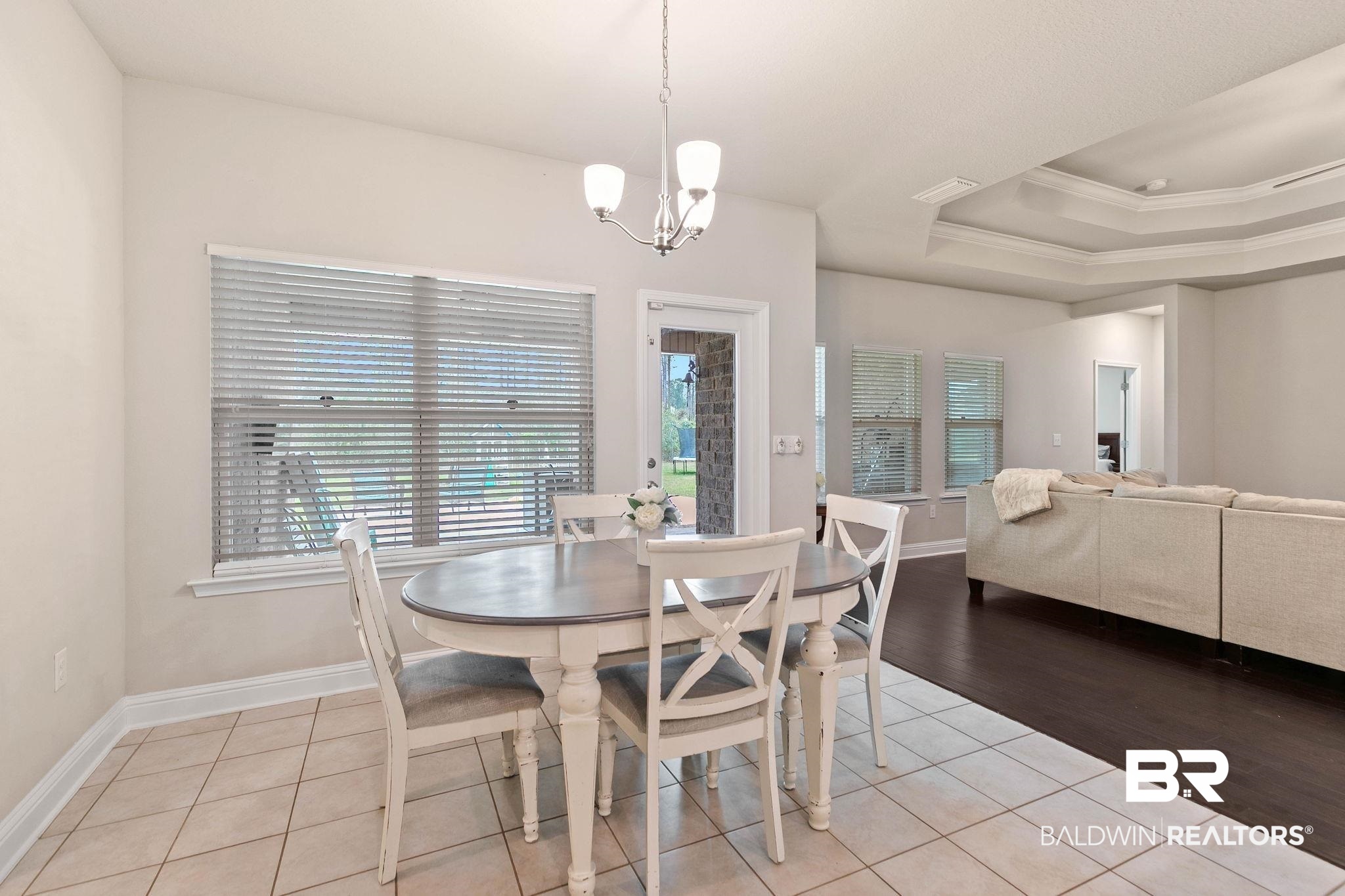 12750 B Jenkins Pit Road Daphne, AL 36527 - Photo 29 of 89 Dining room with light tile patterned floors, a chandelier, ornamental molding, and a tray ceiling