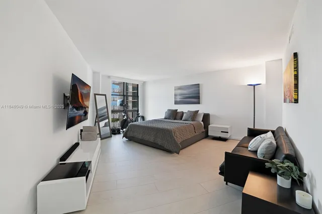 a bedroom with a bed a flat screen tv and window