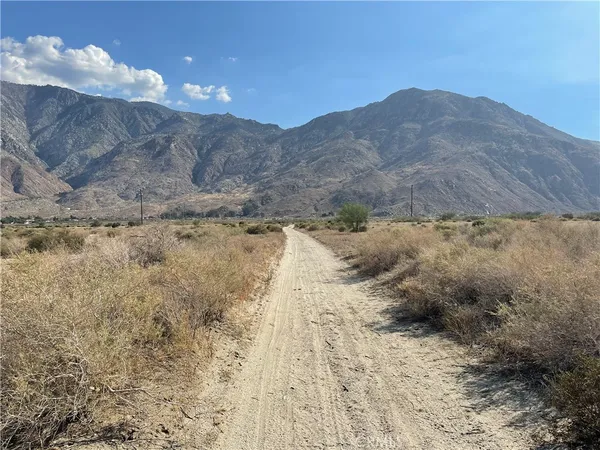 a view of a dry yard with mountains in the background