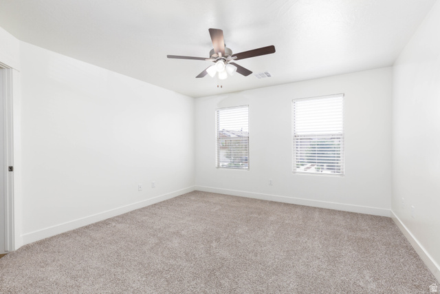 3157 Deseret Drive St. George, UT 84790 - Photo 10 of 24 Spacious room featuring neutral carpeting, white walls, two windows with blinds, a ceiling fan, and baseboard trim