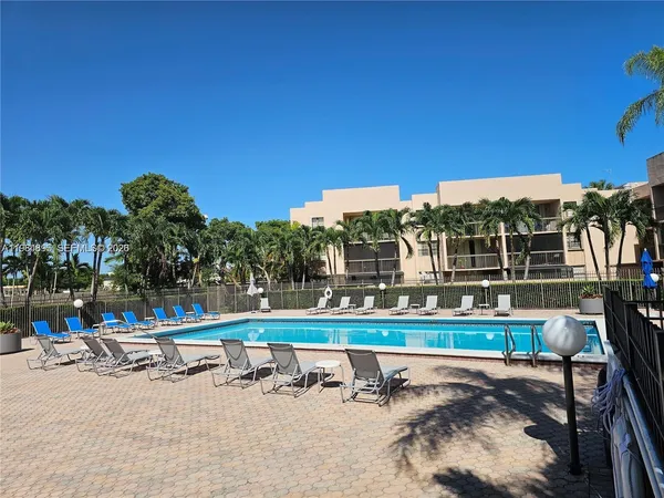 a view of a swimming pool with a bench and trees in the background