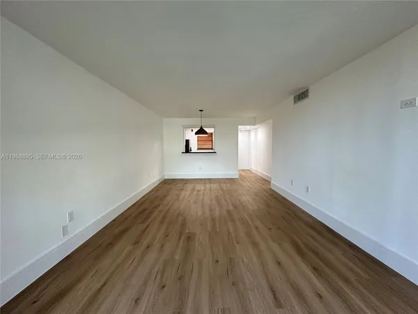 a view of a big room with wooden floor and windows
