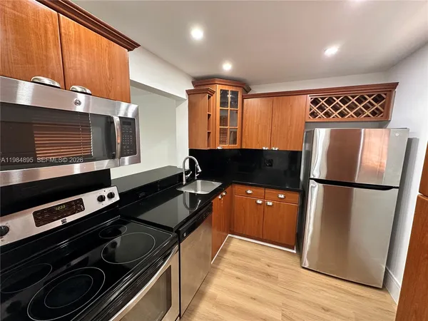 a kitchen with granite countertop a refrigerator and a stove top oven