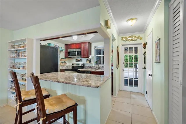 a kitchen with stainless steel appliances granite countertop table chairs and a refrigerator