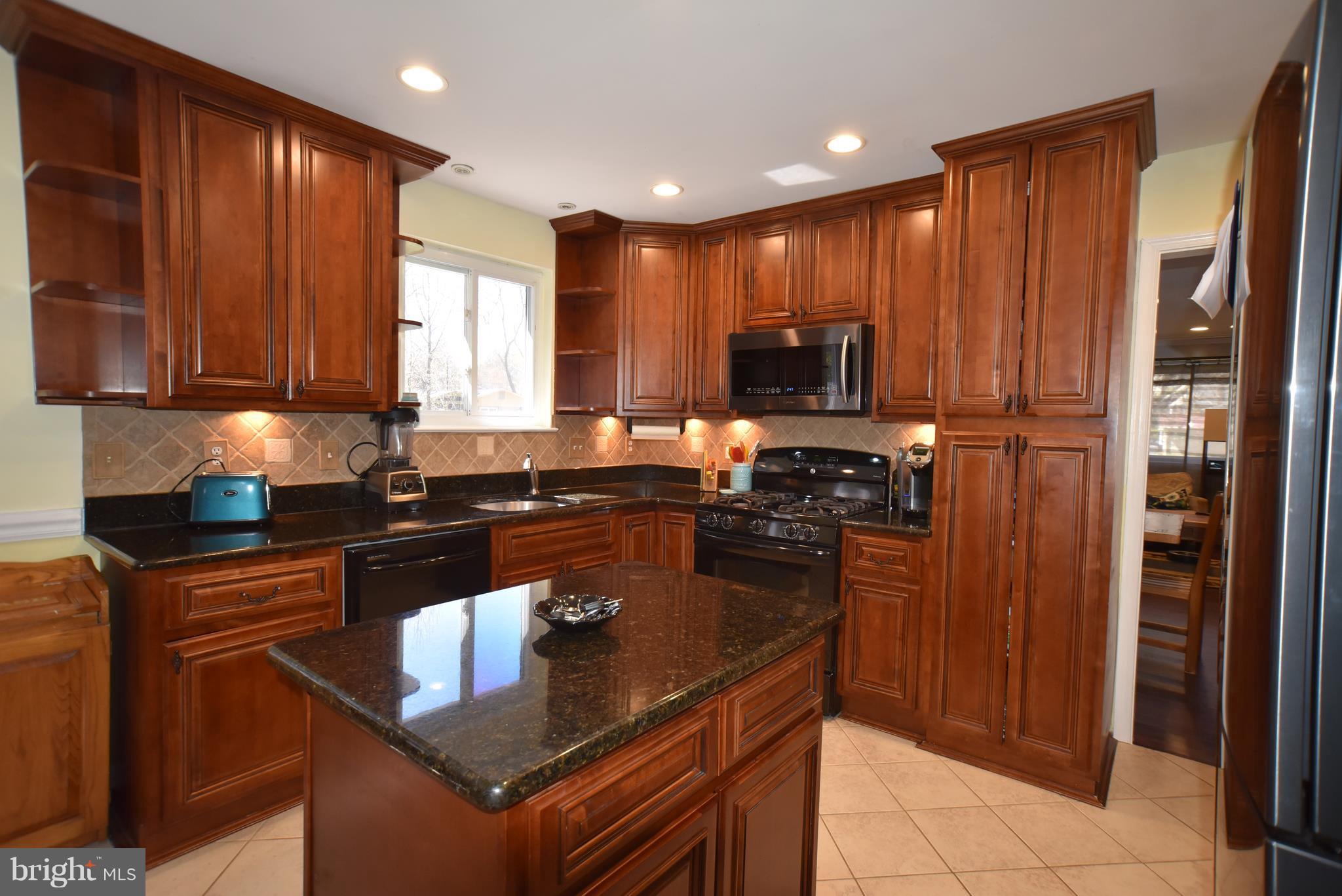 8645 Victoria Road Springfield, VA 22151 - Photo 2 of 19 a kitchen with kitchen island granite countertop a refrigerator a sink and wooden cabinets