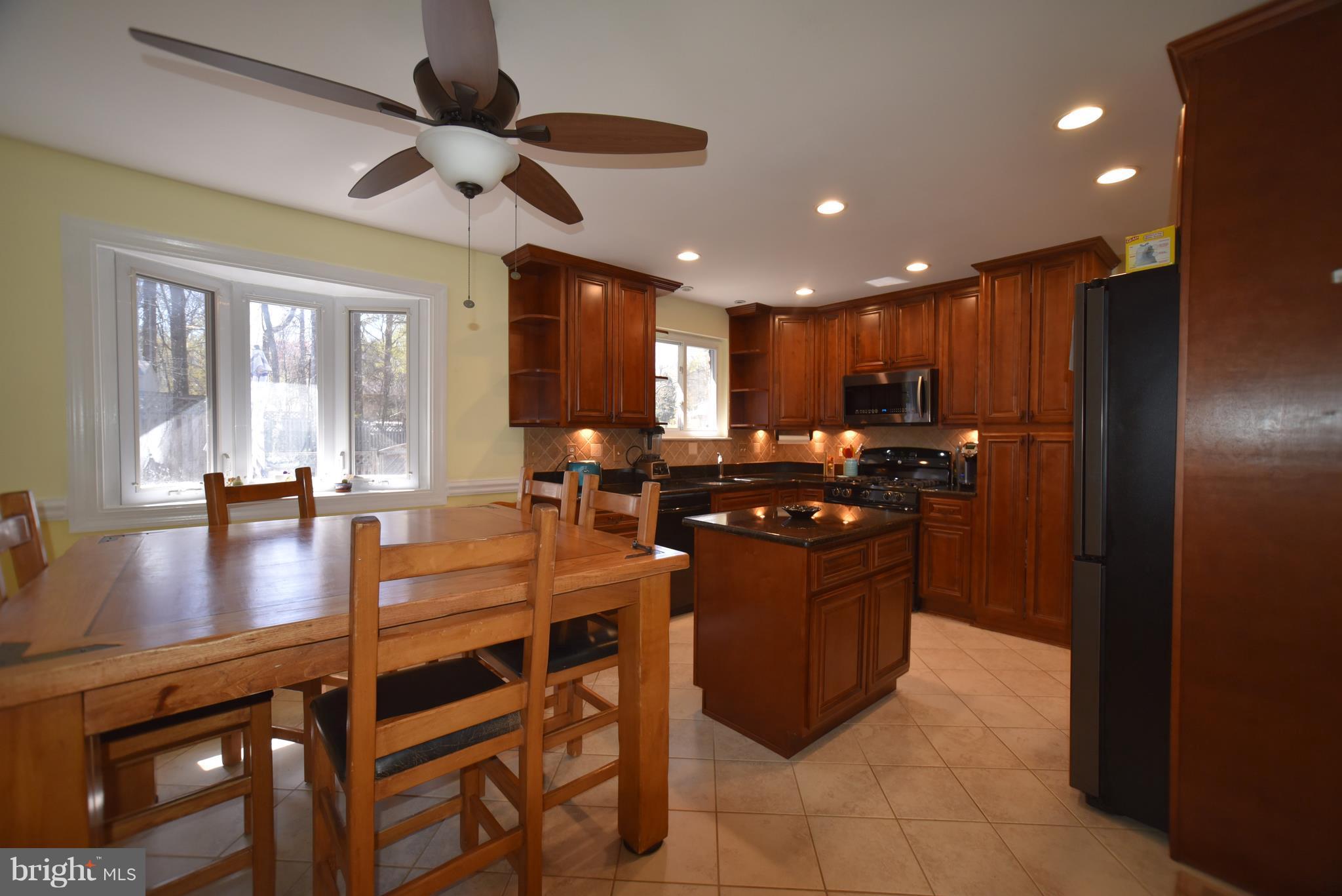 8645 Victoria Road Springfield, VA 22151 - Photo 3 of 19 a kitchen with stainless steel appliances granite countertop a refrigerator a stove a sink a dining table and chairs with wooden floor