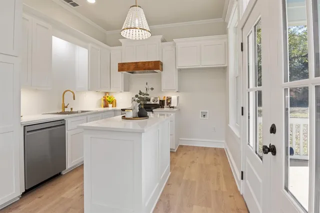 a kitchen with white cabinets and window