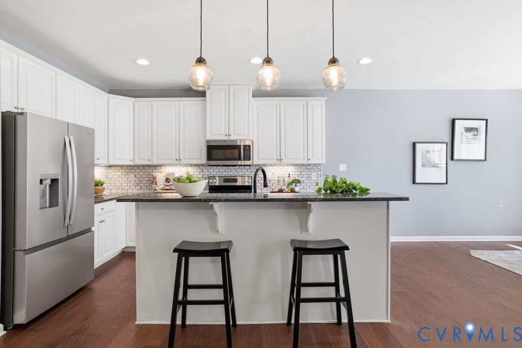 8712 Bailey Hill Road Midlothian, VA 23112 - Photo 12 of 46 a kitchen with stainless steel appliances a table chairs refrigerator and microwave