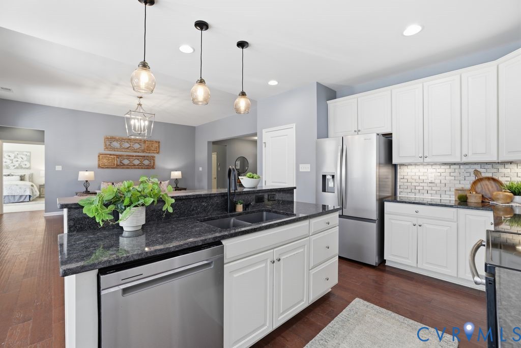 8712 Bailey Hill Road Midlothian, VA 23112 - Photo 14 of 46 a kitchen with stainless steel appliances kitchen island granite countertop a refrigerator a sink dishwasher a dining table and chairs with wooden floor