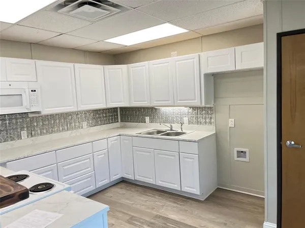 a kitchen with granite countertop a sink a counter top space and cabinets