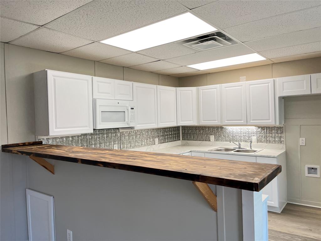 5259 Fm 156 Street North, Unit 6 Krum, TX 76249 - Photo 4 of 16 a kitchen with granite countertop a sink a counter top space and cabinets