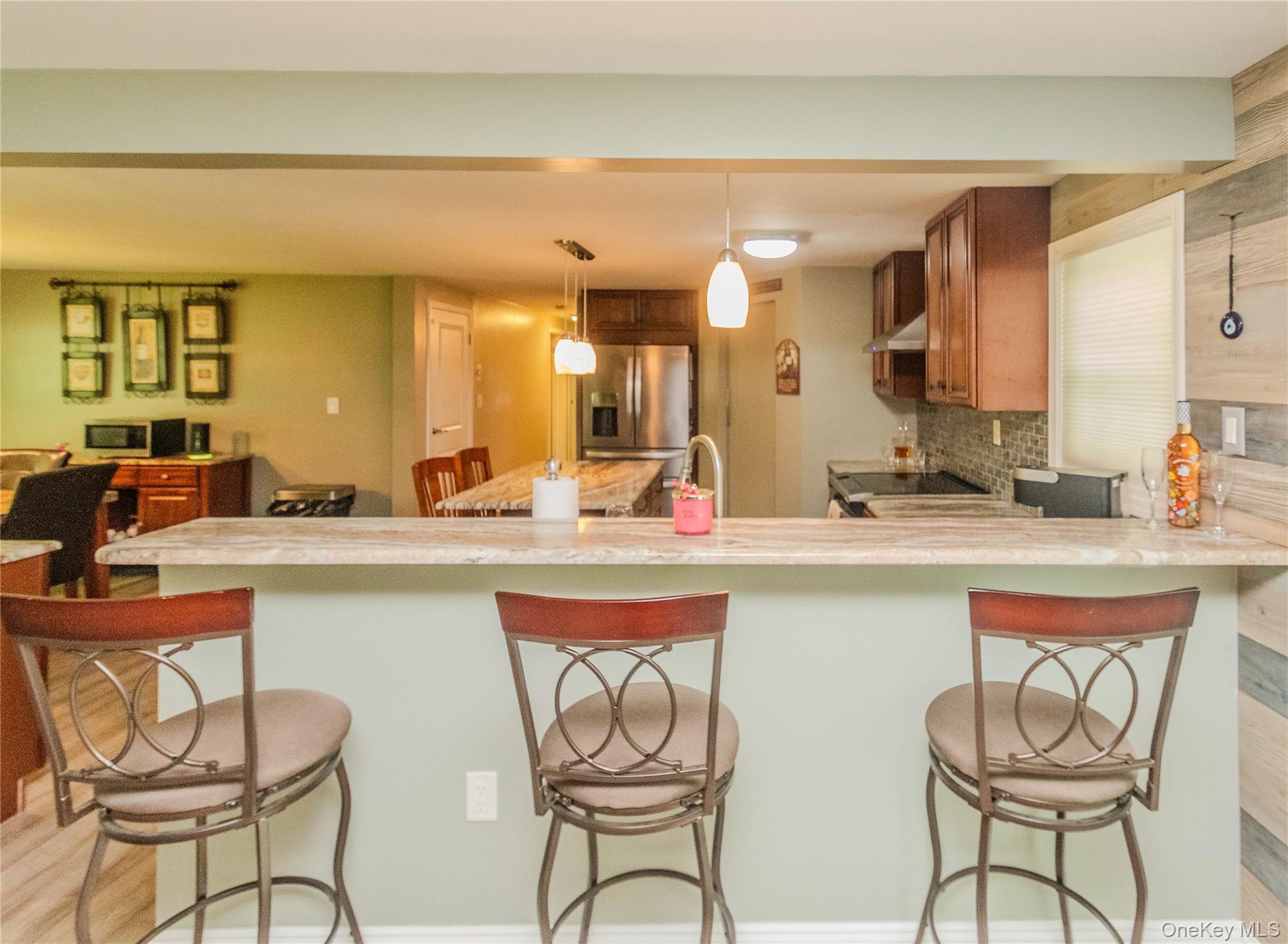 15 Van Dewark Road Middletown, NY 10941 - Photo 6 of 41 Kitchen featuring an extended breakfast bar with stone-finish countertop, wood-finish cabinetry, stainless steel appliances, and a mosaic tile backsplash