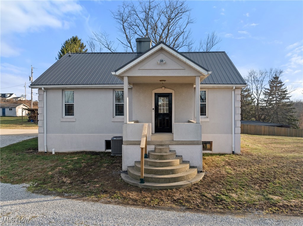 71963 W Road Martins Ferry, OH 43935 - Photo 5 of 39 View of front of home featuring a chimney, central AC unit, metal roof, and stucco siding
