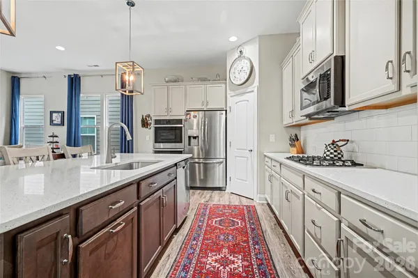 a kitchen with stainless steel appliances kitchen island granite countertop a refrigerator a stove and a sink with wooden floor