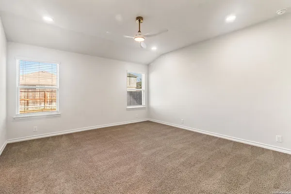 an empty room with windows and chandelier fan