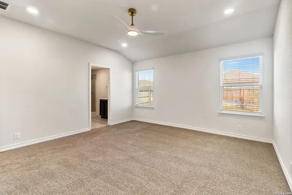 an empty room with windows and ceiling fan