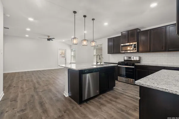 a kitchen with stainless steel appliances granite countertop a sink a stove and a wooden floor