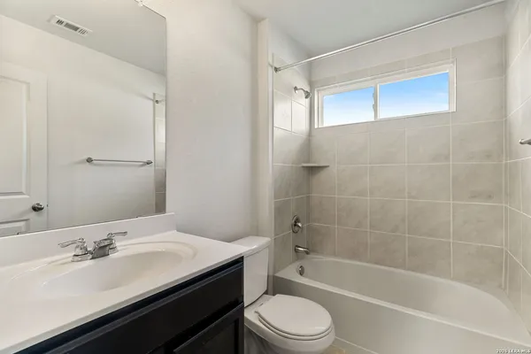 a bathroom with a bathtub shower sink vanity and toilet