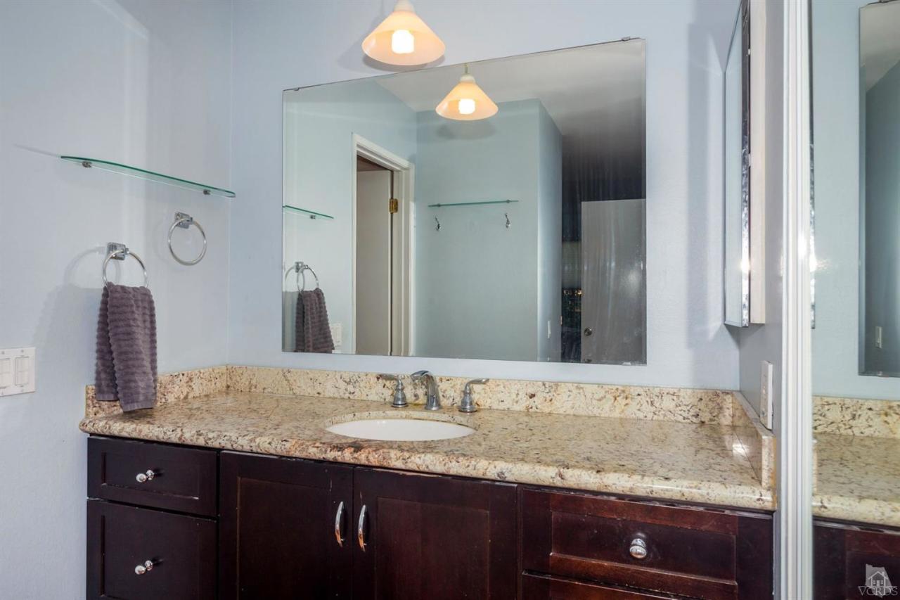 1706 Sinaloa Road, Unit 107 Simi Valley, CA 93065 - Photo 6 of 27 a bathroom with a granite countertop sink and a mirror