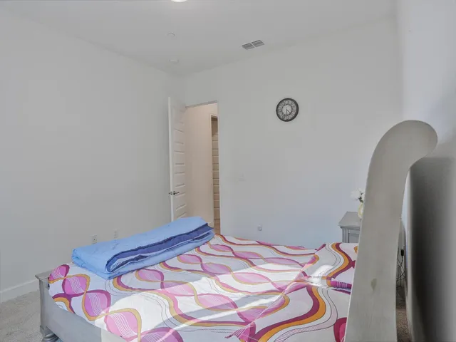 a bedroom with a bed and a lamp on the dresser