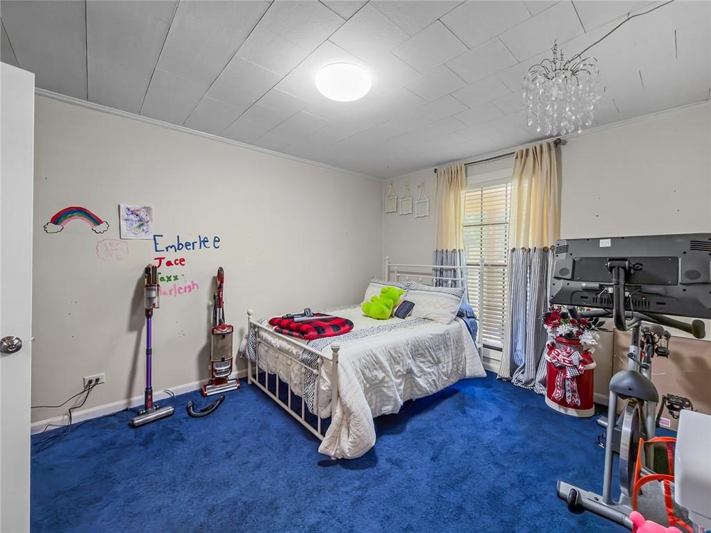 1024 Trail Street Valley, AL 36854 - Photo 21 of 37 Bedroom featuring blue carpeting, ceiling fan with crystal chandelier accent lighting, and large window with shutters and natural light