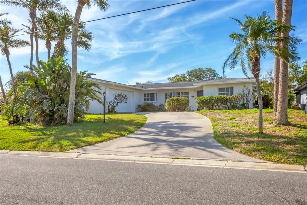 a front view of a house with garden and tree