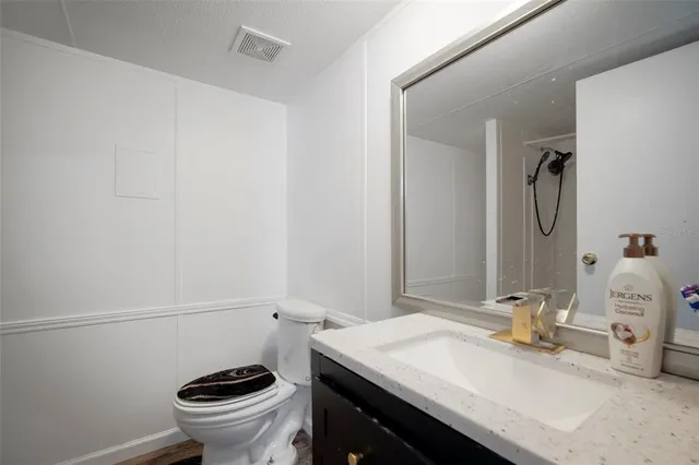 a bathroom with a granite countertop sink a toilet and mirror