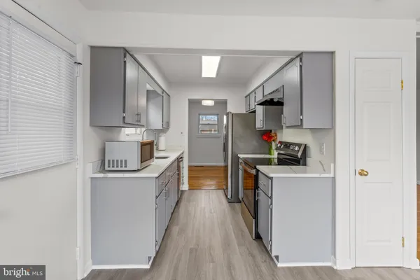a kitchen with stainless steel appliances a stove top oven a sink a refrigerator white cabinets and wooden floor