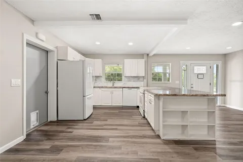 a kitchen with granite countertop white cabinets and white appliances