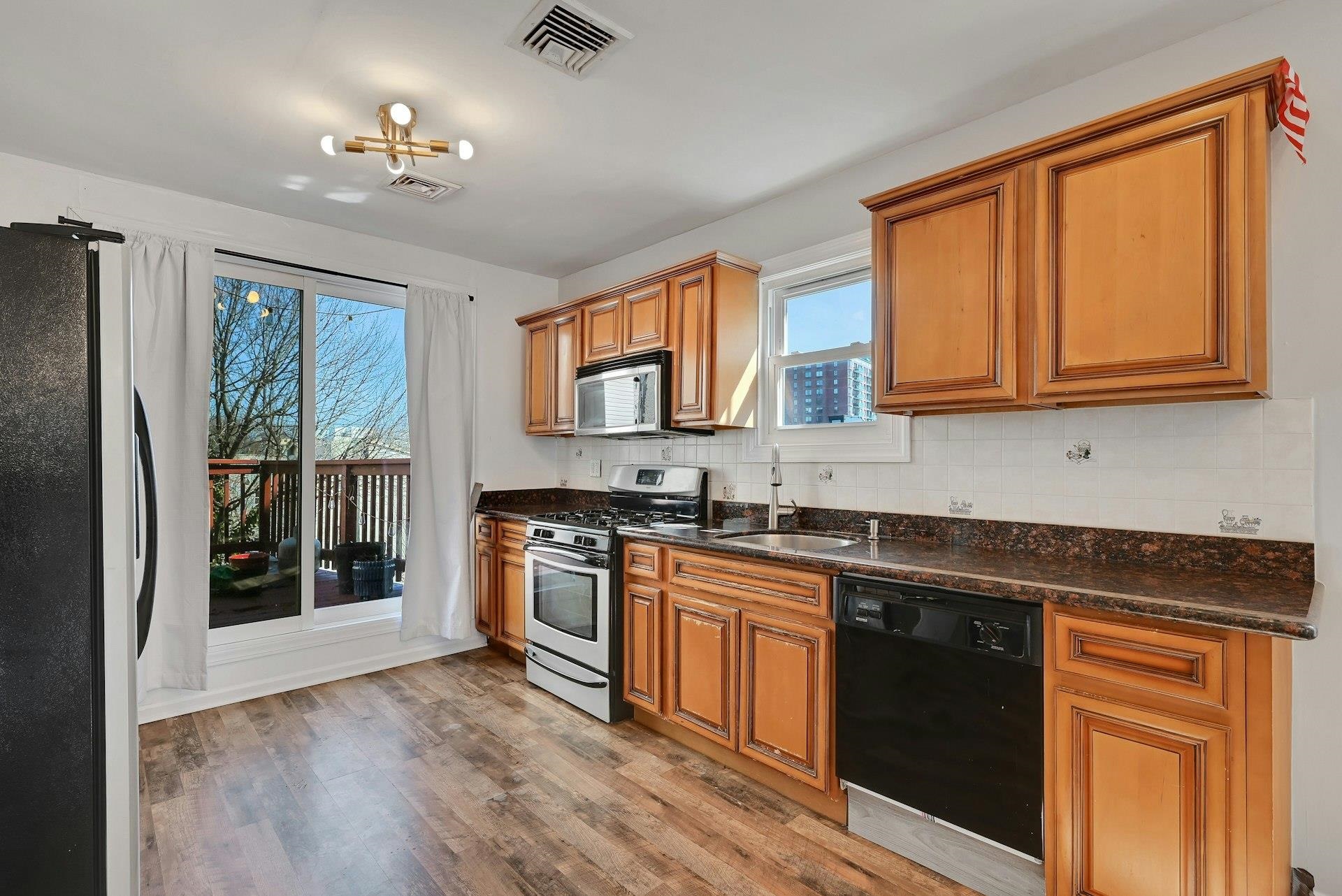 30 Columbia Terrace, Unit 2 Edgewater, NJ 07020 - Photo 5 of 25 a kitchen with stainless steel appliances granite countertop a stove a sink dishwasher a refrigerator and cabinets with wooden floor
