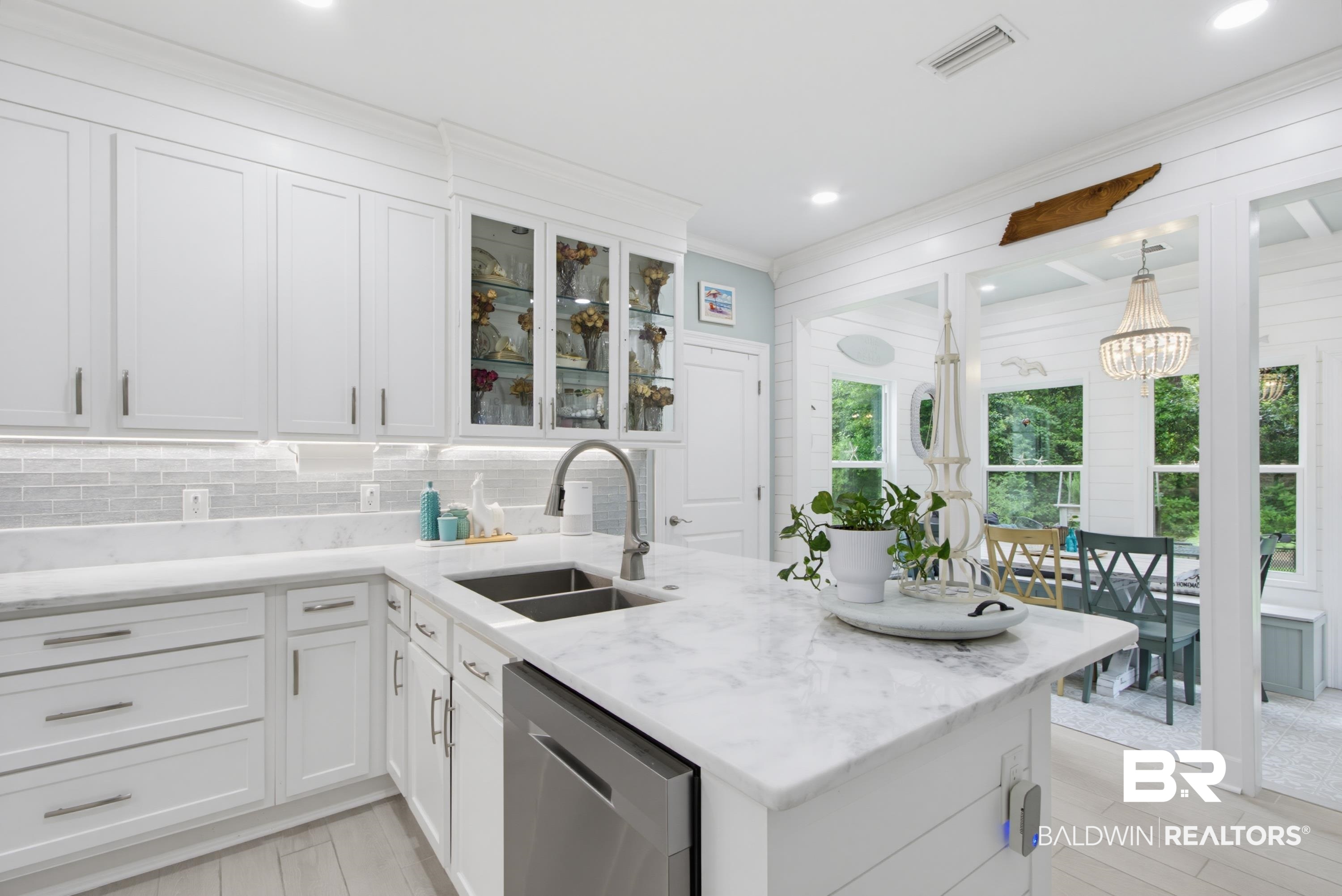 7472 Coopers Landing Road Foley, AL 36535 - Photo 9 of 40 Kitchen featuring white shaker-style cabinetry, a built-in stainless steel dishwasher, a double basin undermount sink with a gooseneck faucet, light-toned tile wood-finish flooring, and a stone countertop with a matching backsplash