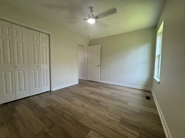 a view of an empty room with window and wooden floor