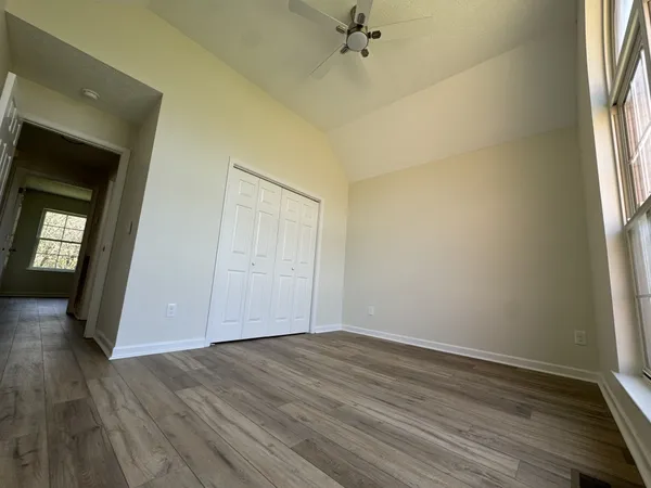 a view of an empty room with a window and wooden floor