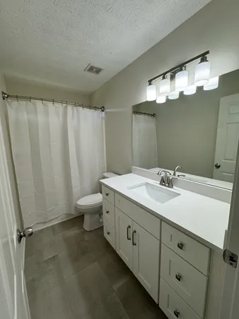 an empty room with wooden floor ceiling fan and windows