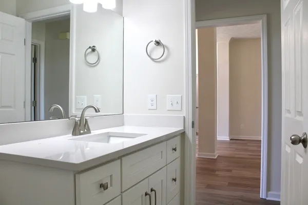 a view of a hallway with wooden floor and a bathroom