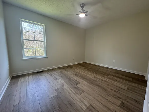 an empty room with wooden floor and windows