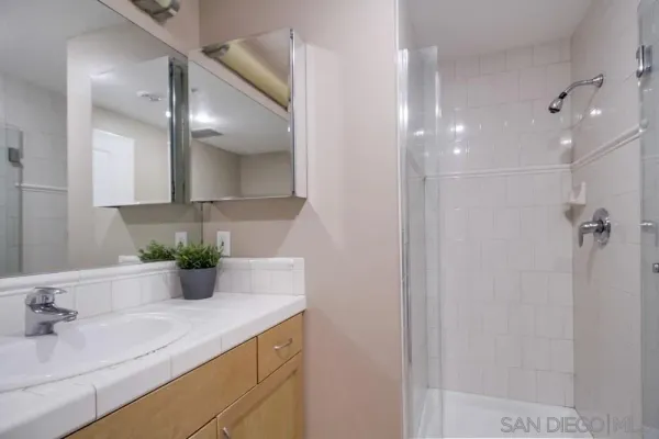 a bathroom with a granite countertop sink a mirror and shower