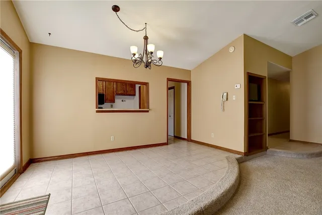 a view of a livingroom with a fireplace a chandelier and windows