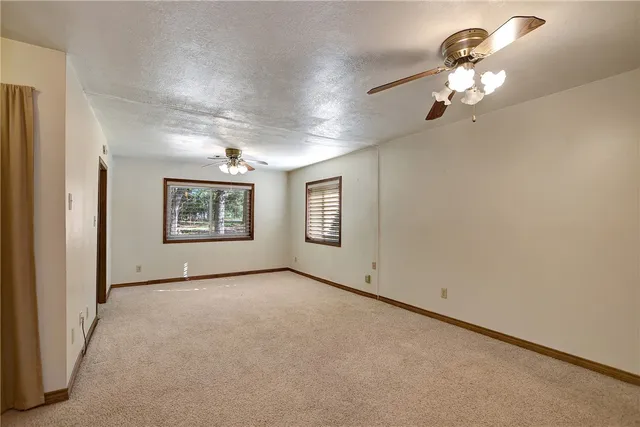 an empty room with chandelier fan and closet