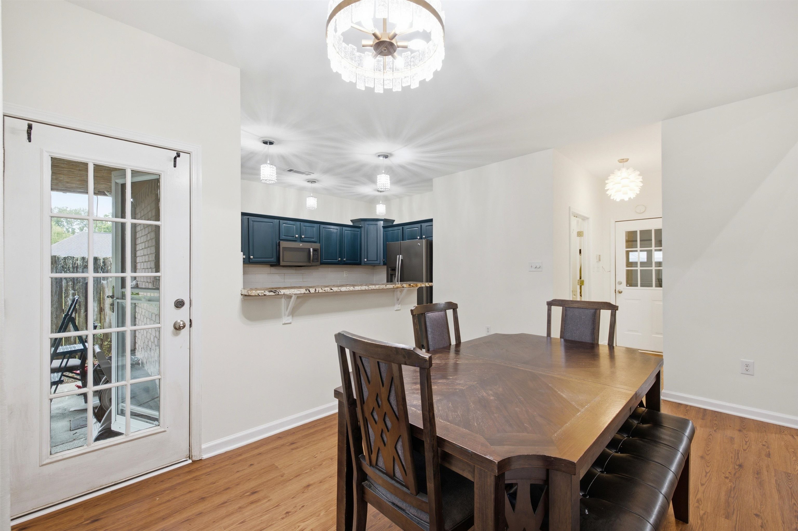 96 Berryfield Cove Collierville, TN 38017 - Photo 16 of 39 Open concept living space featuring wood-finish flooring, a contemporary chandelier, a kitchen with blue cabinetry and a breakfast bar, and a glass-paned door