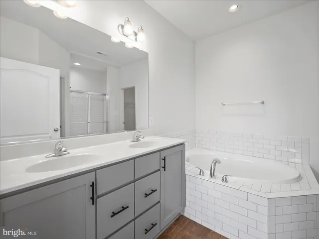 a bathroom with a bathtub a double vanity sink and mirror