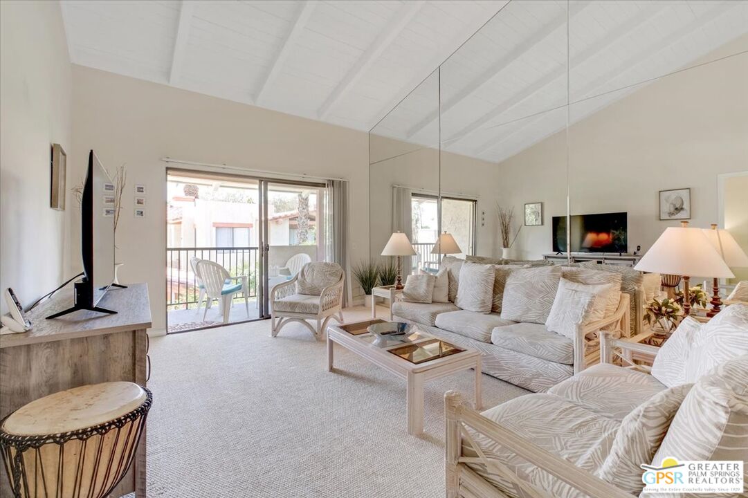 1421 North Sunrise Way, Unit 34 Palm Springs, CA 92262 - Photo 12 of 34 a living room with furniture a flat screen tv and a floor to ceiling window