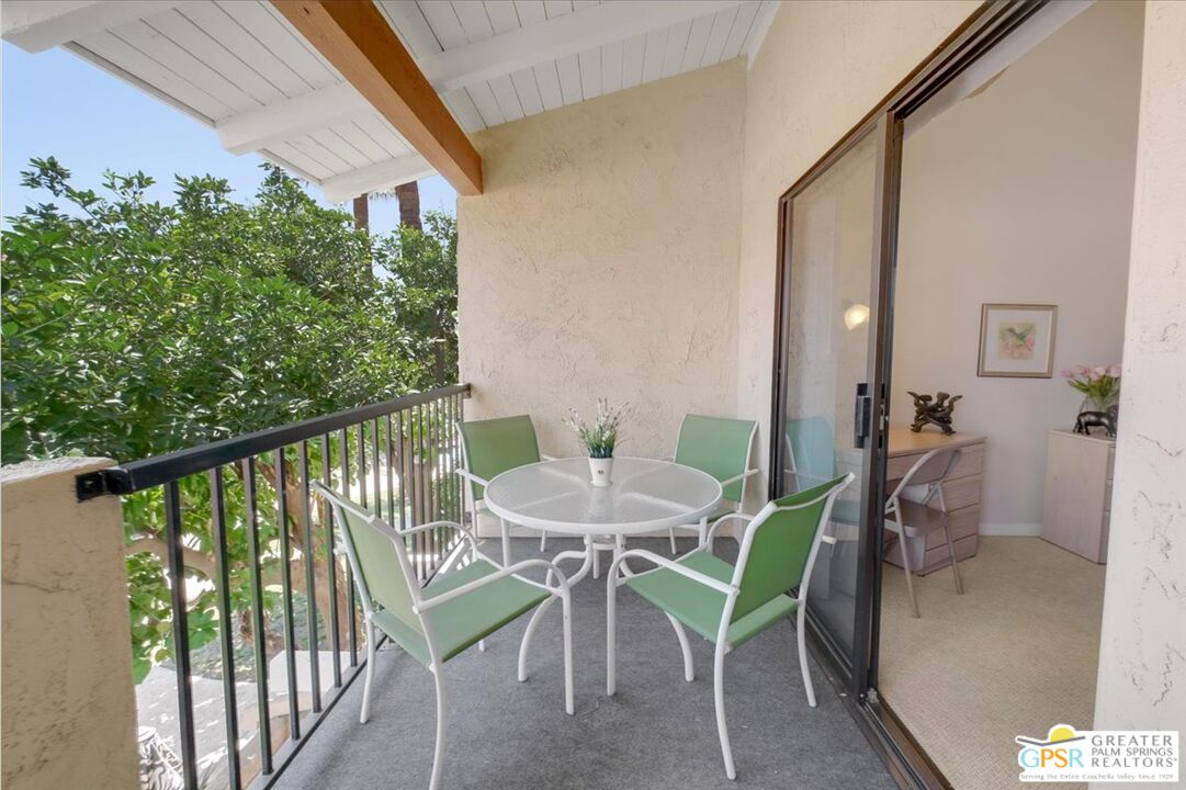 1421 North Sunrise Way, Unit 34 Palm Springs, CA 92262 - Photo 14 of 34 a balcony with table and chairs and potted plants with wooden floor