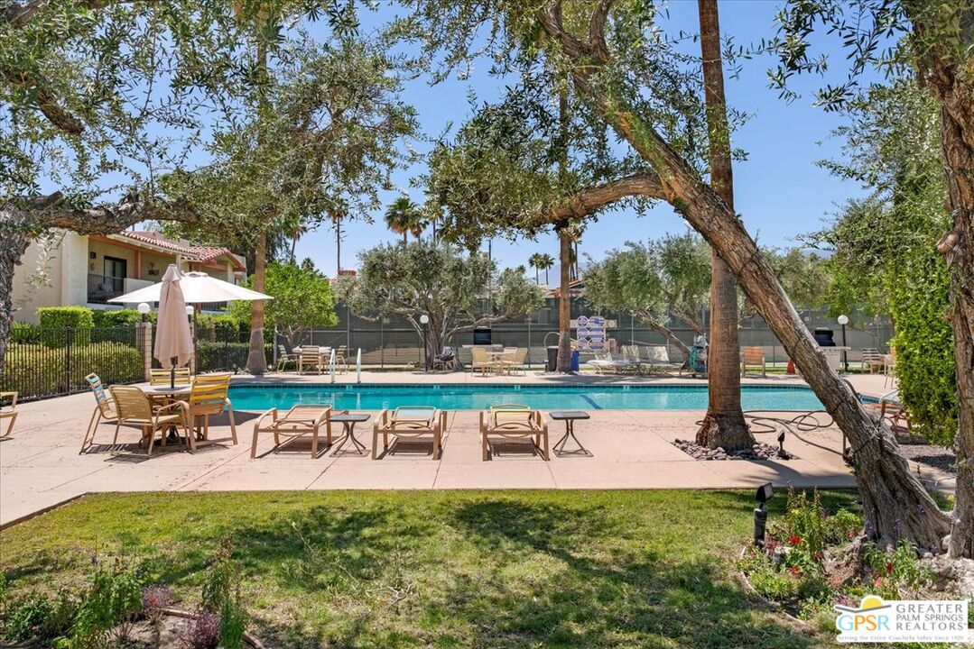 1421 North Sunrise Way, Unit 34 Palm Springs, CA 92262 - Photo 28 of 34 a view of a swimming pool with a bench and trees