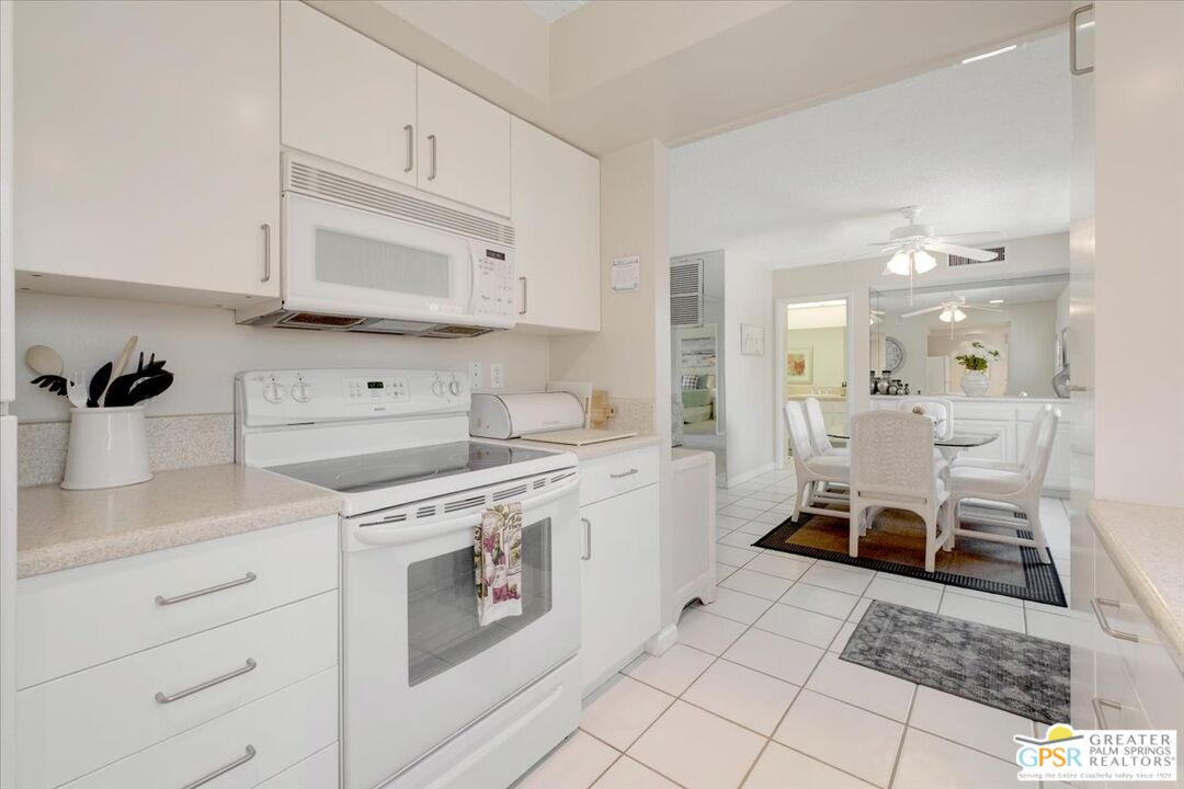 1421 North Sunrise Way, Unit 34 Palm Springs, CA 92262 - Photo 8 of 34 a kitchen with a stove and white cabinets