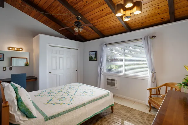 a bedroom with a bed next to a window with a flat screen tv
