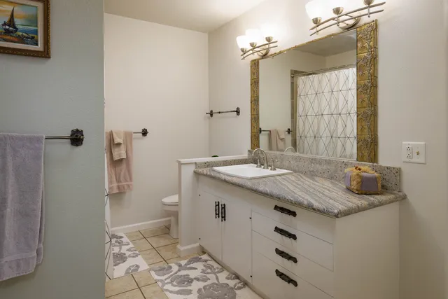 a bathroom with a granite countertop sink toilet and shower