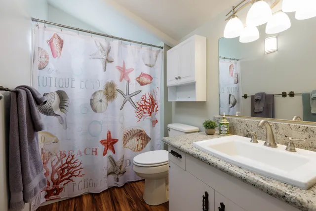 a bathroom with a granite countertop bathtub sink vanity mirror and toilet