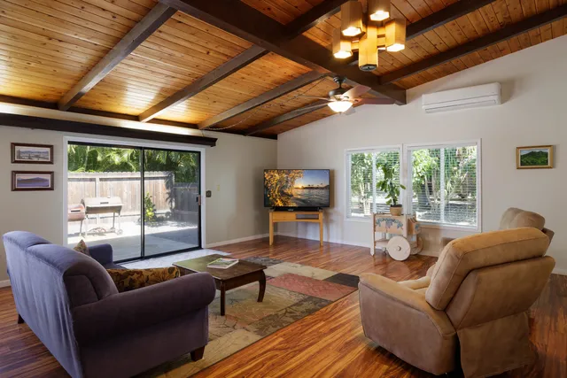 a living room with furniture a ceiling fan and a large window
